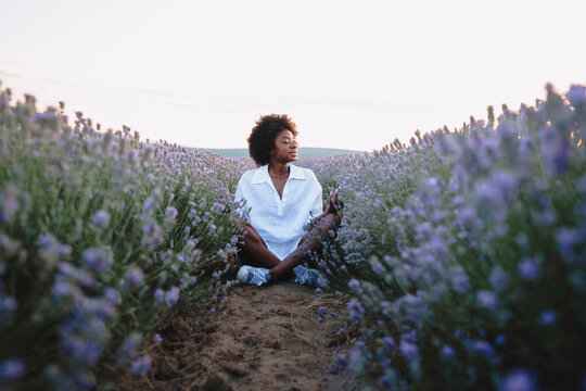 Young woman with eyes closed meditating in lavender field