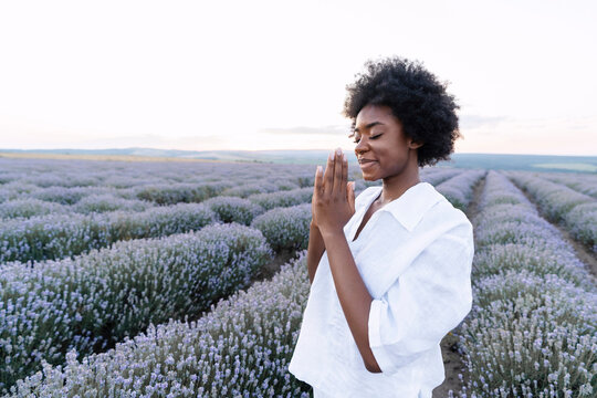 Smiling woman with prayer pose standing in lavender field