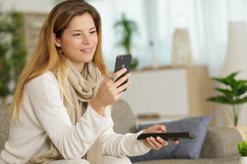 Fototapeta na wymiar woman using smartphone while holding remote control