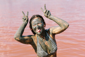 Smiling woman showing peace sign near lake