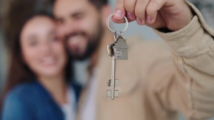 Affectionate couple by the Christmas tree in their kitchen, showcasing keys to their new residence. Joyful newlyweds commemorating first home purchase, a cherished New Year present, homeownership.