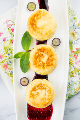 lush and tall cheesecakes with jam and mint on a white plate top view