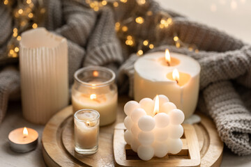 A cozy composition with candles, a knitted element and a garland.
