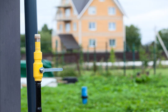 Natural gas pipeline with a closed tap on the background of a cottage
