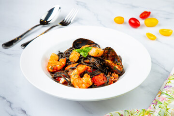 black noodles with mussels, shrimp, tomatoes and herbs side view
