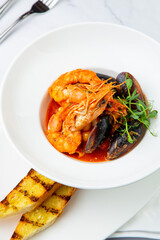 cooked shrimp with herbs and mussels on a white plate, side view