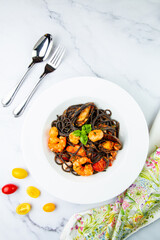 black noodles with mussels, shrimp, tomatoes and herbs top view