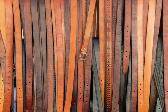 Muchas correas de cuero, colgadas en exhibición en la calle comercial. Correas de cuero artesanales a la venta con un cierre central.