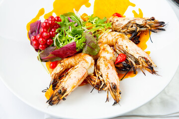 cooked shrimp with herbs and berries on a white plate, side view
