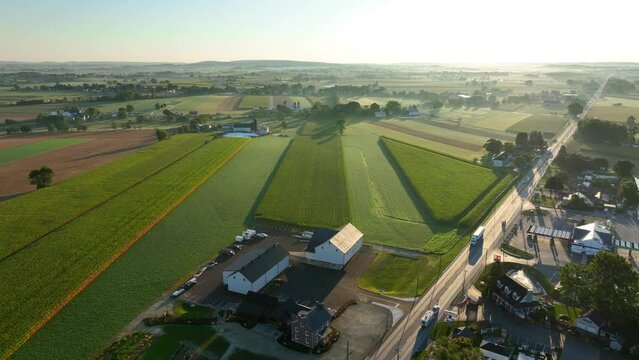 Rural farmland and town in USA. Aerial truck shot during morning sunrise in late summer. Corn fields and rolling hills.