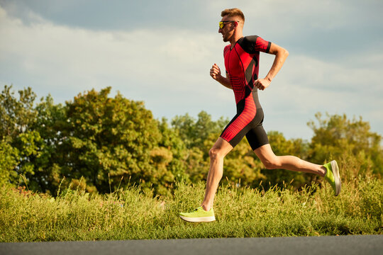 Dynamic image of competitive man in sportswear, athlete training outdoors on summer day, running. Marathon. Concept of professional sport, triathlon preparation, competition, athleticism