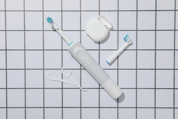 Electric toothbrushes and dental floss on light background, top view