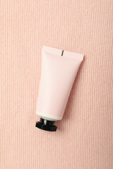 Cosmetic tube on pink background, top view