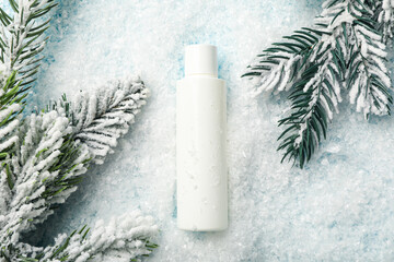 Cosmetic bottle, fir branches and snow on light background, top view