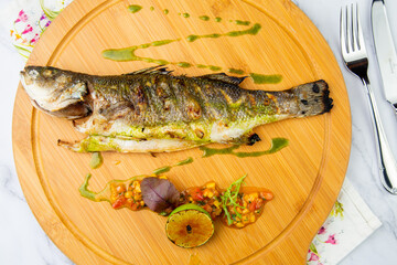 baked fish with spices and lemon on a wooden tray side view