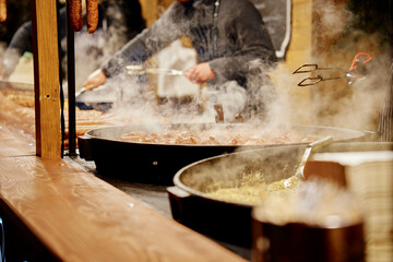 Process of cooking street food outdoors. Frying pan with fried dishes. Christmas Fair at Wroclaw main square