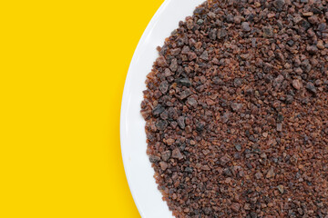 Black himalayan salt on yellow background.