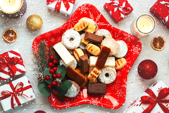 Top view of Nougat christmas sweet,mantecados and polvorones with christmas ornaments on a christmas star shaped red plate. Assortment of christmas sweets typical in Spain
