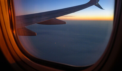 Window view of airplane wing and beautiful clouds at sunset, USA. - obrazy, fototapety, plakaty