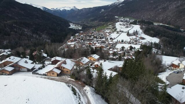 Elevation of a drone in the direction of the city of Saint-Jean-de-Sixt through the houses of the hill during the day, France
