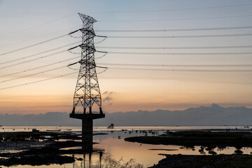 Silhouette of high voltage tower and electric line with the sunset background on the west coast of Taiwan.