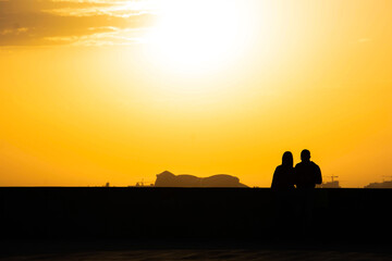 Fototapeta na wymiar Sunset and lovers. Woman and man against the backdrop of sunset. Orange sky and sun
