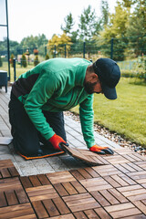 A man installing wood floor planks, building a beautiful terrace