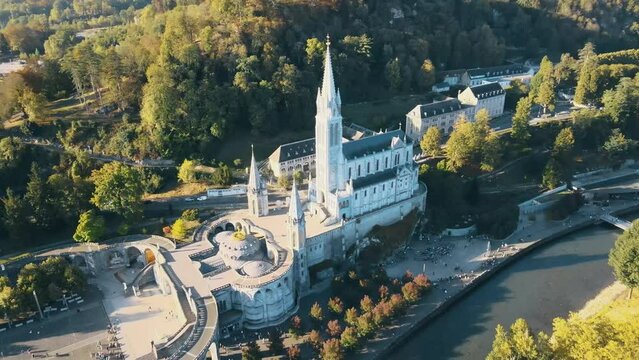 Aerial tilting establishing shot of the Lourdes Cathedral with tourists outside