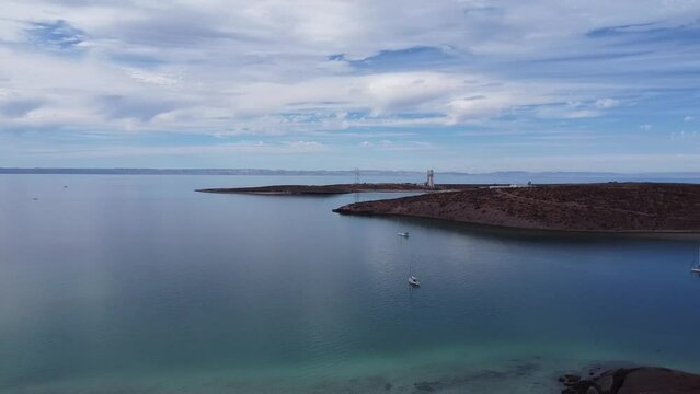 Panorama aerial shot of a distinct desert landscape in front of the calm blue sea of Baja California Sur Mexico playa el tecolote beach near La Paz with view of floating boats in the sea