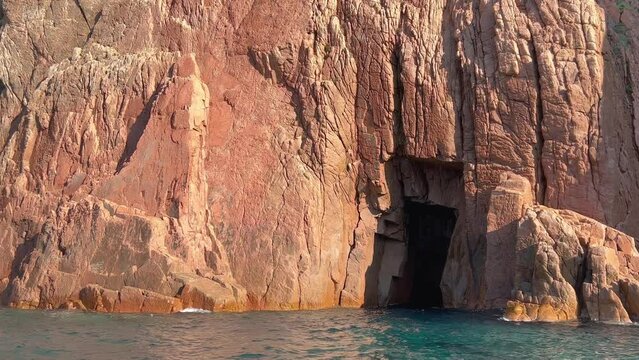 Hole in rock formation of jagged coast of Calanques de Piana seen from moving boat on Mediterranean Sea in Corsica island in summer season, France