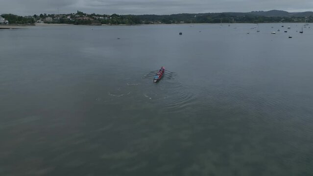 Aerial tracking shot of Trainera rowing team training on coast of Ares, Spain