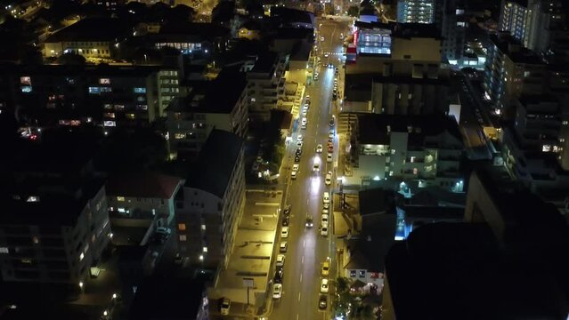 City, commercial and night with lights from a drone pov for travel, transportation or commute with office buildings. Traffic, street and skyscraper architecture with cars driving in the evening