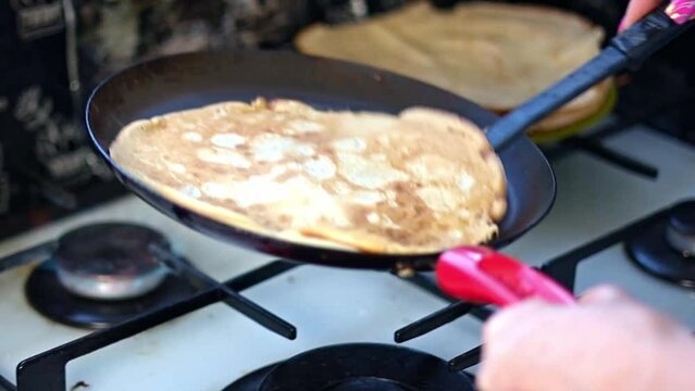 Large round pancake in a frying pan. Cooking smoke rises from the pancake. Pancakes with holes. Maslenitsa. Russian tradition. Cooking.