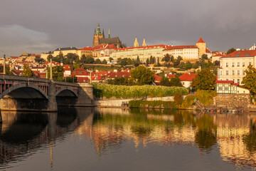 Fototapeta na wymiar Autumn views from Prague. Picturesque autumn Prague in the morning sun. The Vltava River with the Charles Bridge, the waterfront and houses of Mala Strana and the dominant Prague Castle. Czechia