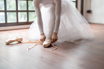 Ballerina in ballet shoes. Asian girl tying ribbons of toe shoes. ballet dancer preparing and wearing ballet shoes in dance studio prepares for a rehearsal.