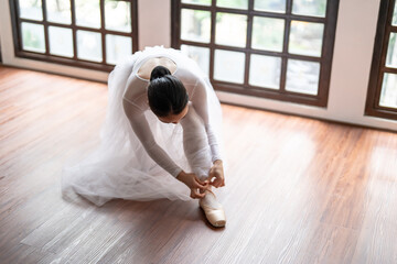 Ballerina in ballet shoes. Asian girl tying ribbons of toe shoes. ballet dancer preparing and wearing ballet shoes in dance studio prepares for a rehearsal.