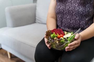 Zelfklevend Fotobehang Asian Overweight woman dieting Weight loss eating fresh fresh homemade salad healthy eating concept Obese Woman with weight diet lifestyle. © Charlie's