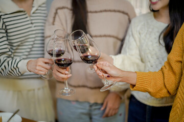 Cheerful friends enjoying home Birthday holiday party. Asian Friends cheering drinking red wine celebrating Christmas or New Year party