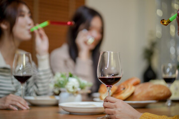 Cheerful friends enjoying home Birthday holiday party. Asian Friends cheering drinking red wine celebrating New Year party.