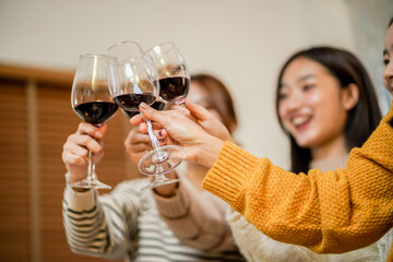 Cheerful friends enjoying home Birthday holiday party. Asian Friends cheering drinking red wine...