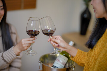 Cheerful friends enjoying home Birthday holiday party. Asian Friends cheering drinking red wine celebrating Christmas or New Year party