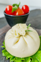 Italian cheese burrata is served on a round plate with basil and tomatoes with a fork and knife on the background of an old tree