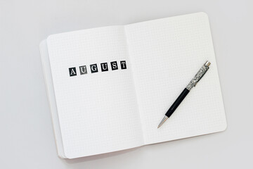 Filling in the diary, writing August in a notebook in a dot
