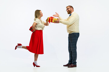 Happy winter holidays. Happy, cheerful couple, man and woman dressed retro fashion outfit with gave presents for each other against white background