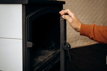 Man's hands open the fireplace. Home furnace for space heating. Fireplace stove 