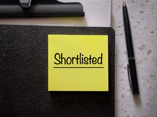 Business and work management concept. Shortlisted written on a notepad. With blurred styled...