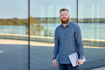 Successful aspiring businessman man with red beard enjoys warm weather while walking around the city