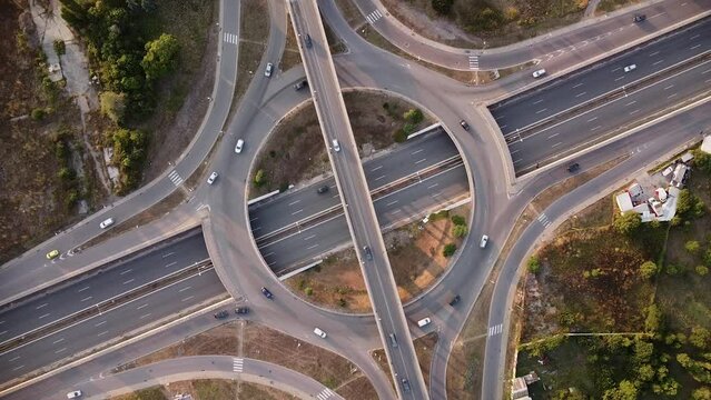 Aerial drone footage of a freeway intersection. Multi level intersection in Europe filmed from above. Multi-level junction road with moving cars at sunset.
