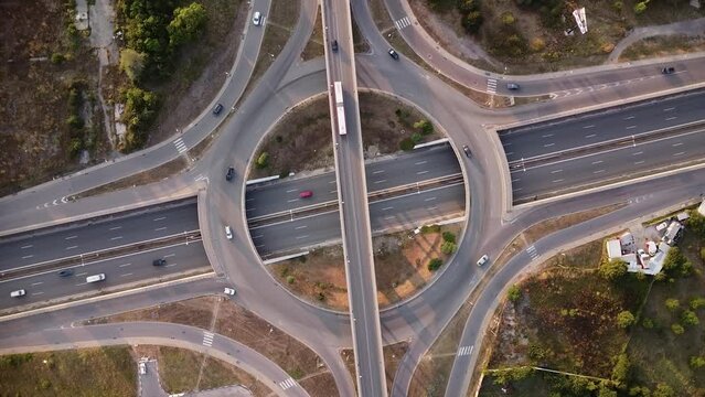 Aerial drone footage of a freeway intersection. Multi level intersection in Europe filmed from above. Multi-level junction road with moving cars at sunset.
