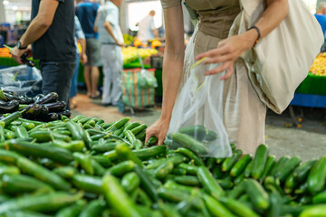 Woman choosing cucumbers at farmer market, close-up - obrazy, fototapety, plakaty